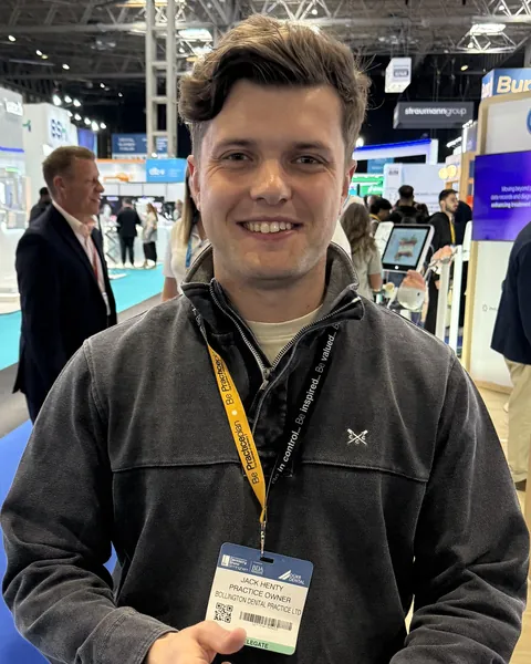 Jack Henty at a dental trade show, smiling, wearing a delegate badge that reads Practice Owner, Bollington Dental Practice